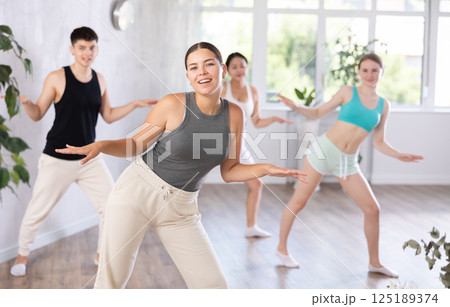Girl teen perform choreographic exercise and teach energetic mobile social dance groove with friends 125189374