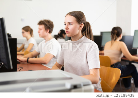 Clever female teenager solving tasks of computer science, using pc and printer in the auditory 125189439