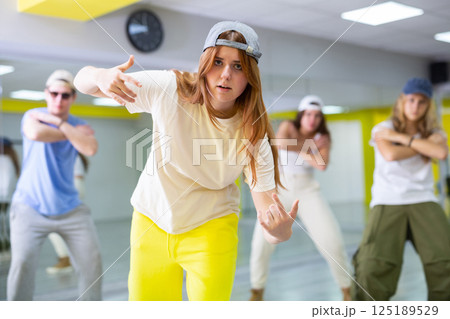 Young girl in cap training breakdance Toprock moves in dance hall Young girl in cap training breakdance Toprock moves in dance hall 125189529