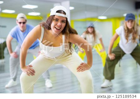 Boy and girls dancing synchronous group choreography in dance hall Boy and girls dancing synchronous group choreography in dance hall 125189534