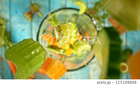 Falling pieces of fruits and vegetables into blender. 125189808
