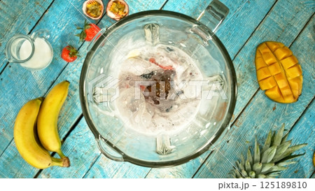 Fresh smoothie drink. Preparing smoothie in a blender. Mix of fruit and vegetable with milk. 125189810