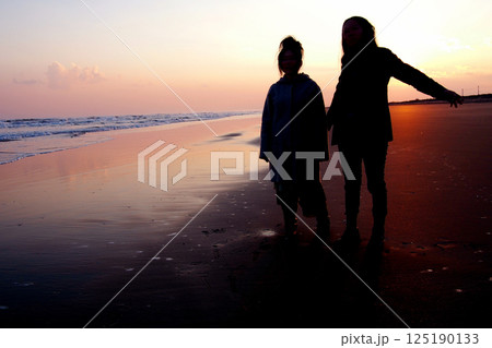 夕暮れの海辺に立つ女性二人 夕暮れの海辺に立つ女性二人 125190133
