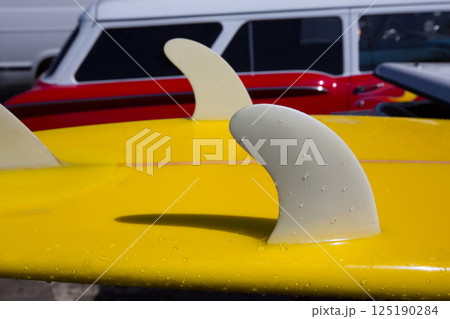 Yellow surfboard keel fins detail eith red retro car  in California 125190284