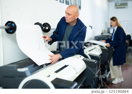 Man using printer while working in print shop 125190864