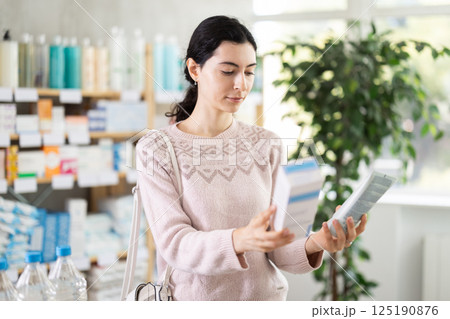 Young woman chooses cream at pharmacy Young woman chooses cream at pharmacy 125190876