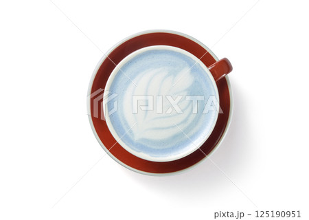 Tasty blue matcha latte with foam in cup on red plate white background 125190951
