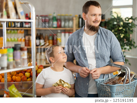 Visiting store, father and son is looking at something on shelf of showcase. Visiting store, father and son is looking at something on shelf of showcase. 125191195