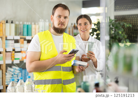 Laborer man builder in pharmacy scans QR code on gel for burns, pharmacist offer help for customer Laborer man builder in pharmacy scans QR code on gel for burns, pharmacist offer help for customer 125191213