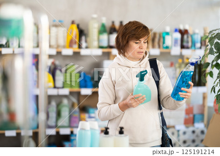 Store visitor woman purchases in household chemicals department, choose multisurface cleaner spray 125191214