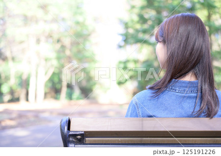 公園でリラックスする若い女性の後ろ姿 125191226
