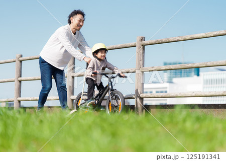 自転車の練習をする5歳の男の子とサポートする父親 125191341
