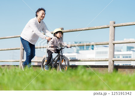 自転車の練習をする5歳の男の子とサポートする父親 125191342