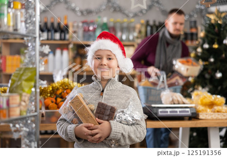 Boy in Santa hat holding nougat in the store Boy in Santa hat holding nougat in the store 125191356