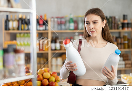 Young woman choosing milk in grocery store 125191457