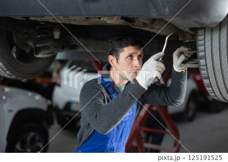 Service station man employee works in repair box, department 125191525