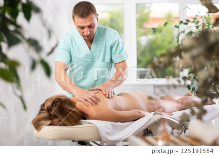 The masseur makes a massage to woman 125191584