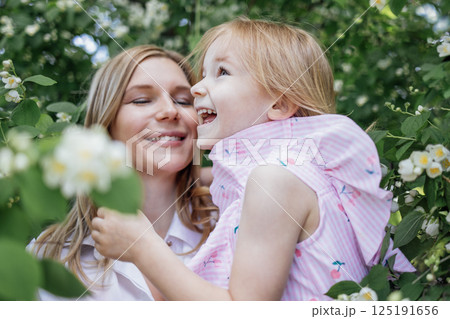 Laughing cute little girl and adorable mom together in jasmine flowers. Laughing cute little girl and adorable mom together in jasmine flowers. 125191656