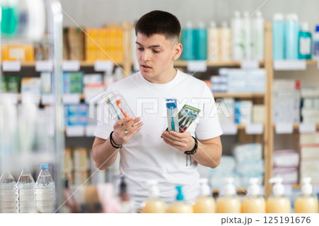 Portrait young man choosing best toothbrush at pharmacy Portrait young man choosing best toothbrush at pharmacy 125191676