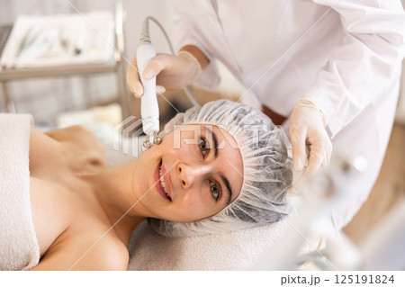 Young woman receiving cosmetic facial radiofrequency facial procedure Young woman receiving cosmetic facial radiofrequency facial procedure 125191824