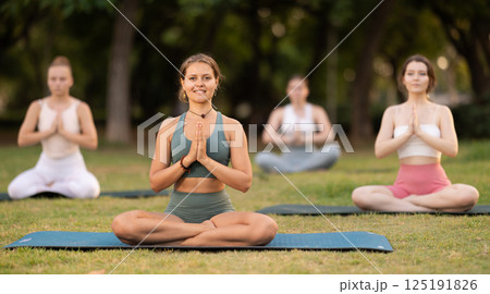 Lotus pose - young pretty girls doing yoga outdoors 125191826