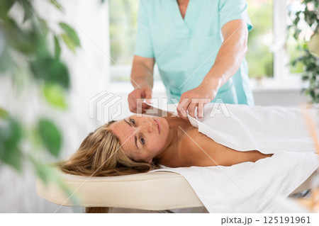the man ensures the woman is comfortably covered with a towel for the massage. 125191961