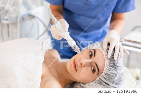 Woman receiving cosmetic facial procedure with hydrogen and oxygen ions attachment 125191966