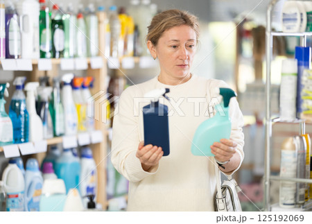 Adult woman chooses cleaning spray in store 125192069