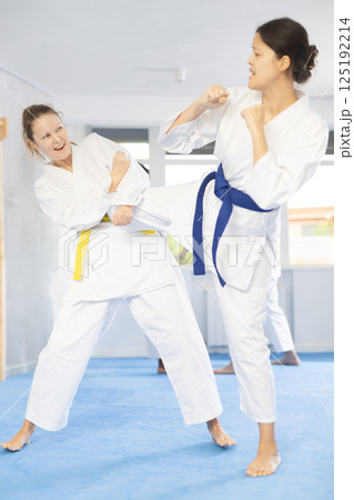 Karate with two female athletes practicing, training and sparring in fight class. Healthy, fit and active women in uniform learning self defense for safety 125192214