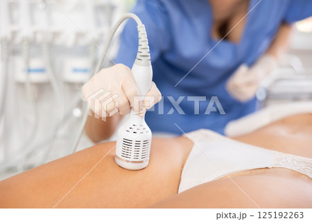 Young female cosmetologist performs whitening procedure on thighs of young woman 125192263