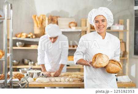 Woman seller holding basket with homemade bread in bakery 125192353