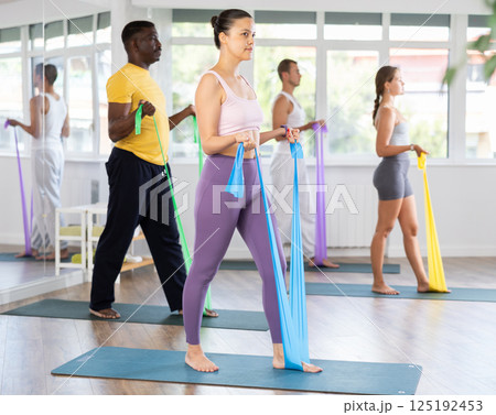 Group of athletes train in Pilates class using elastic bands 125192453