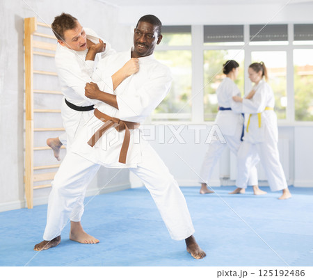 Multinational athletes in pair conduct training battle in oriental fighting technique Multinational athletes in pair conduct training battle in oriental fighting technique 125192486