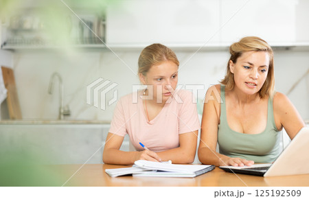 Teenage girl studying at home guided by friendly female tutor 125192509