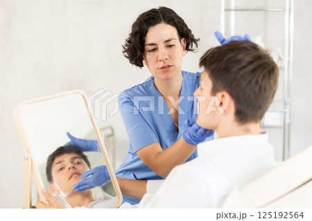 Young man having consultation about face aesthetic while looking in the mirror 125192564