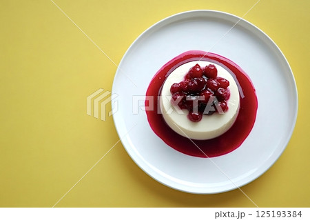 Delicious panna cotta with wild berries and berry sauce on yellow background 125193384