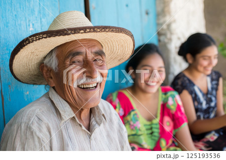 Mexican family smiling together at home with elderly man in sombrero and happy girls 125193536
