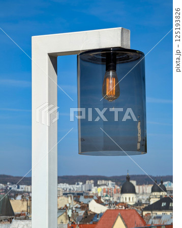Modern lamp with glass shade against clear blue sky. 125193826