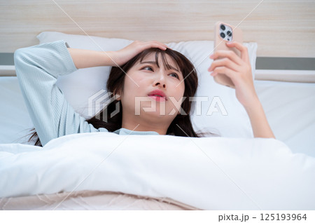スマホを見て頭を抱える若い女性 スマホを見て頭を抱える若い女性 125193964