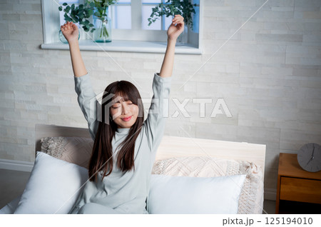 ベッドで伸びをする若い女性 ベッドで伸びをする若い女性 125194010