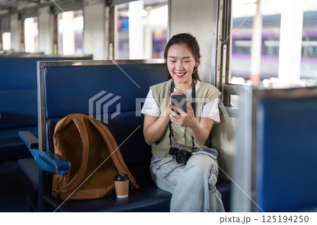 Joy and Exploration. A woman smiles as she interacts with her smartphone on a train journey. 125194250