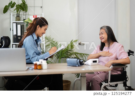 Patient Care and Empathy. A nurse documents information while caring for an elderly patient in a comfortable setting. 125194277