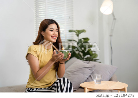 Morning Routine and Healthy Eating. A woman enjoying a nutritious salad as part of her morning routine. 125194278