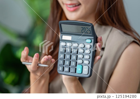 Calculator Insights and Financial Planning. A woman revealing her calculator displaying a financial figure. 125194280