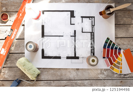 Plan of renovation of house on old wooden table. Top view. Sheet of paper with cans of paint and brushes, palette for choosing colors, construction level and roller. Plan of renovation of house on old wooden table. Top view. Sheet of paper with cans of paint and brushes, palette for choosing colors, construction level and roller. 125194498