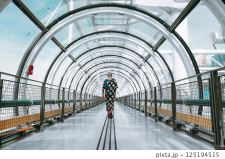 Person Walking in Modern Glass Tunnel Architecture 125194515