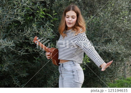 Girl Practices With Ukulele Musical Instrument In The Countryside During A Break 125194635
