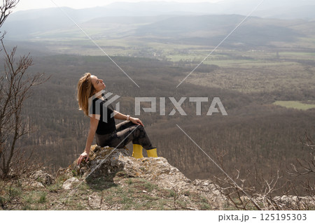 Woman nature viewpoint rests, enjoying scenery, daytime, outdoors, relaxing atop mountain. Woman nature viewpoint rests, enjoying scenery, daytime, outdoors, relaxing atop mountain. 125195303