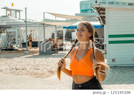 Woman Beach Summer: Young woman adjusts pigtails, sunny beach day, casual summer attire. 125195306