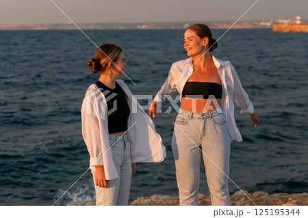 Women Friends Beach Sunset, Two friends enjoy sunset by the sea, creating lasting memories. Women Friends Beach Sunset, Two friends enjoy sunset by the sea, creating lasting memories. 125195344